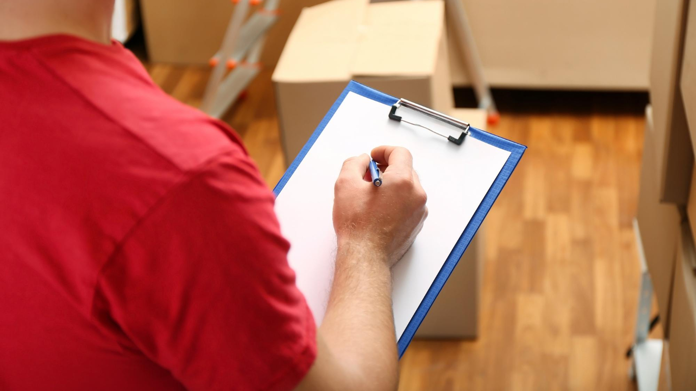 Mover checking inventory list while boxes are prepared for relocation – Easy Best Moves